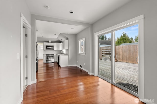 interior space with visible vents, baseboards, a healthy amount of sunlight, and wood finished floors