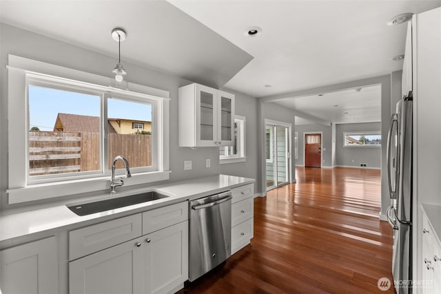 kitchen with glass insert cabinets, dark wood finished floors, white cabinets, stainless steel appliances, and a sink