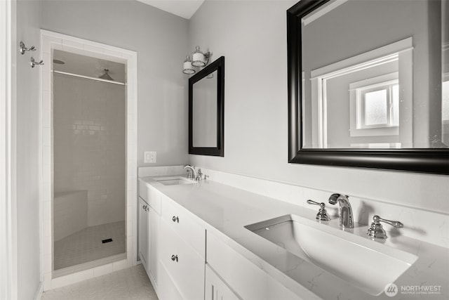 full bath with a sink, a stall shower, double vanity, and tile patterned flooring