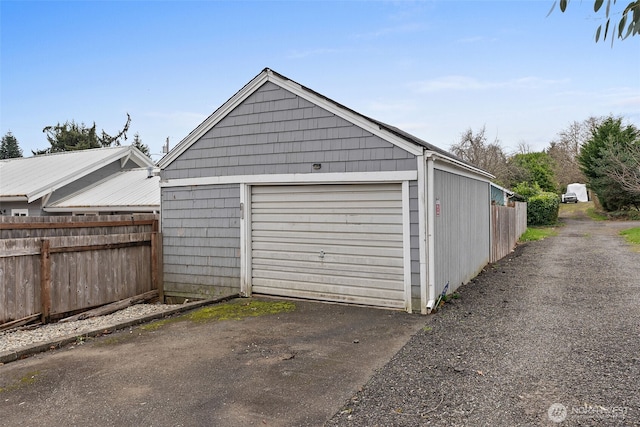 detached garage featuring aphalt driveway and fence