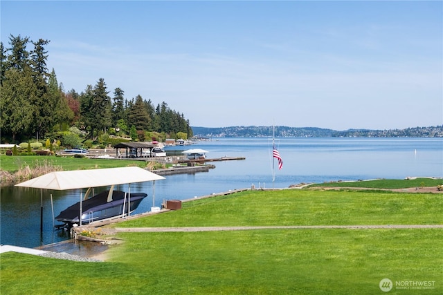 dock area with a water view, boat lift, and a lawn