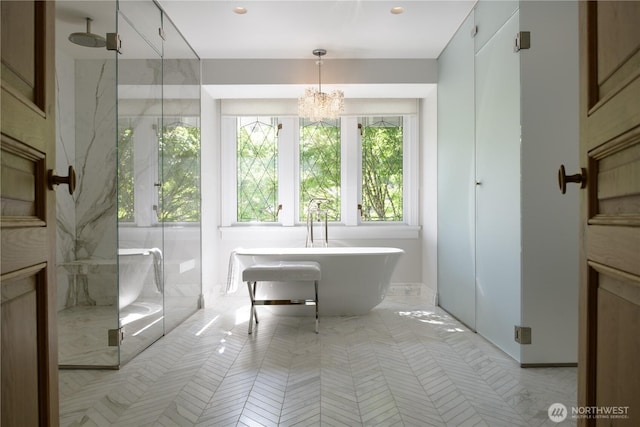 full bathroom featuring a marble finish shower, a freestanding bath, and a notable chandelier