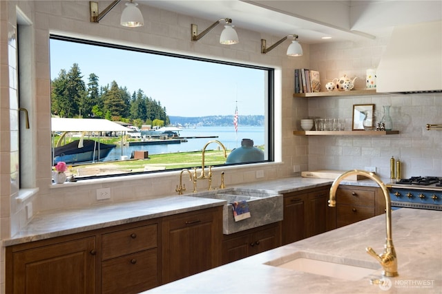 kitchen featuring a sink, decorative backsplash, light stone countertops, and custom range hood