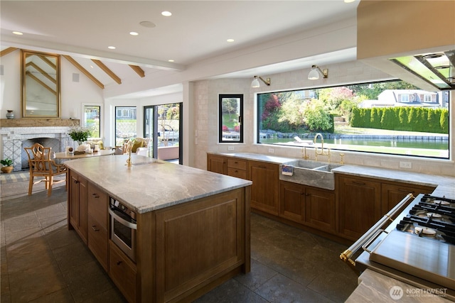 kitchen featuring stone tile floors, a kitchen island, vaulted ceiling with beams, a fireplace, and stainless steel oven