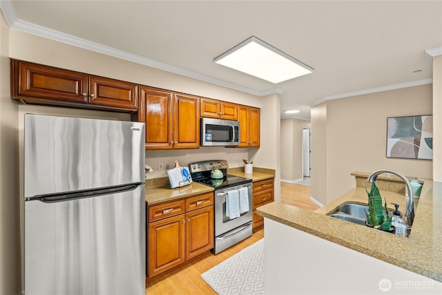 kitchen featuring ornamental molding, brown cabinets, light wood-style floors, stainless steel appliances, and a sink