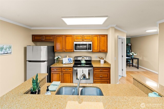 kitchen with light wood-type flooring, brown cabinets, a sink, stainless steel appliances, and crown molding