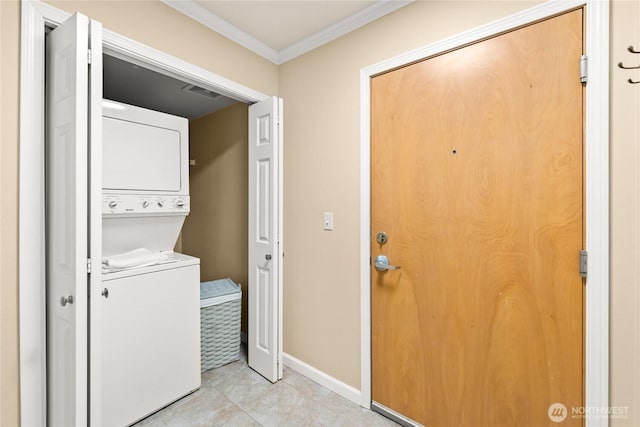 laundry area featuring baseboards, ornamental molding, light tile patterned floors, laundry area, and stacked washer / drying machine