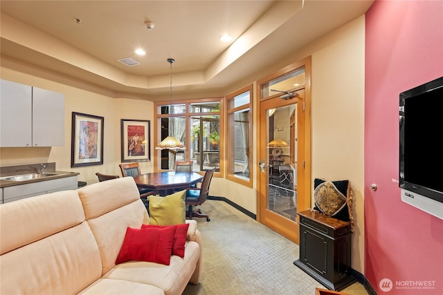 interior space with light carpet, a raised ceiling, a sink, recessed lighting, and baseboards