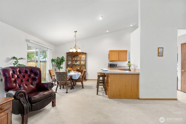 interior space with a notable chandelier, light colored carpet, high vaulted ceiling, and baseboards