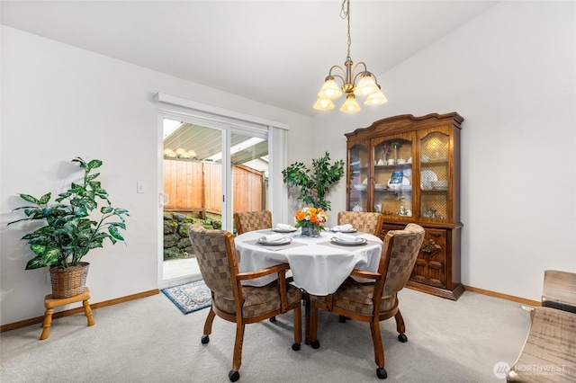 dining space with baseboards, lofted ceiling, light colored carpet, and an inviting chandelier