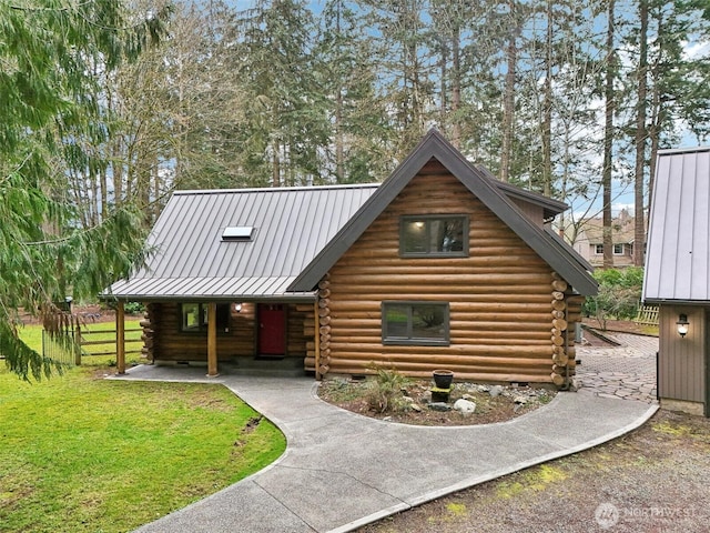 log-style house with a front yard, a standing seam roof, covered porch, log exterior, and metal roof