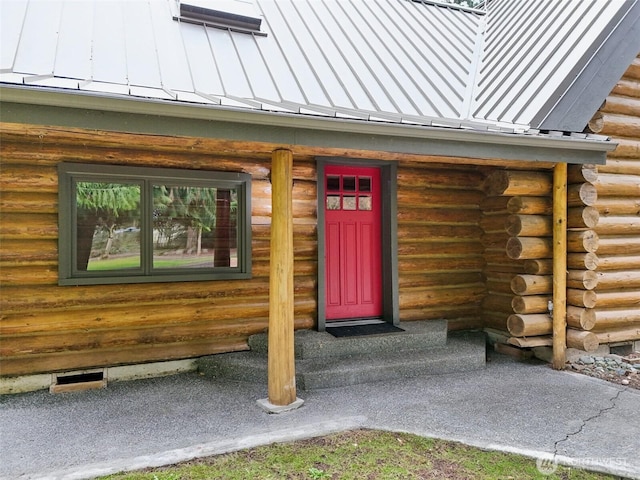 view of exterior entry featuring metal roof, log exterior, and a standing seam roof