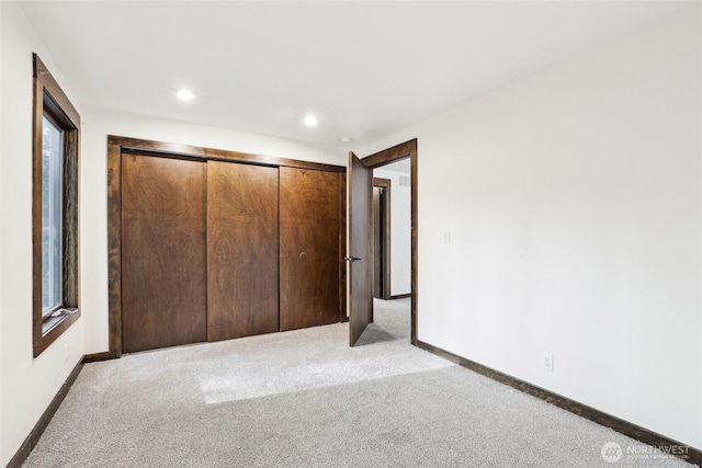 unfurnished bedroom with recessed lighting, baseboards, a closet, and light carpet