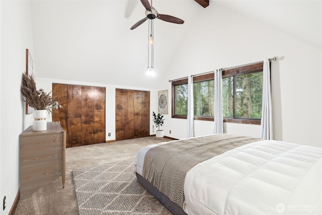 carpeted bedroom featuring ceiling fan, baseboards, multiple closets, and high vaulted ceiling