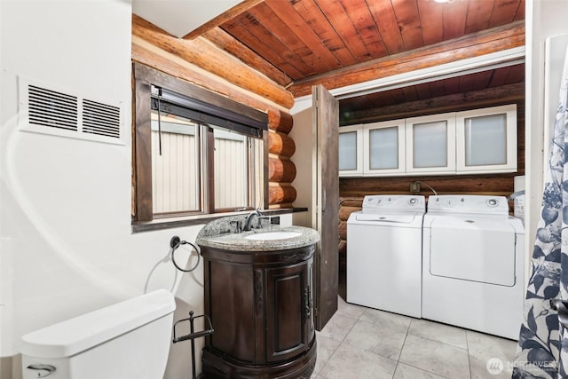 laundry area with visible vents, wood ceiling, rustic walls, independent washer and dryer, and a sink