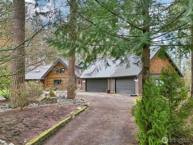 log-style house with a standing seam roof, a detached garage, log exterior, and metal roof