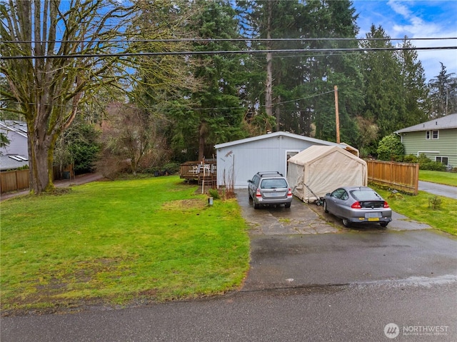 view of front of property with driveway, an outbuilding, a front lawn, and fence