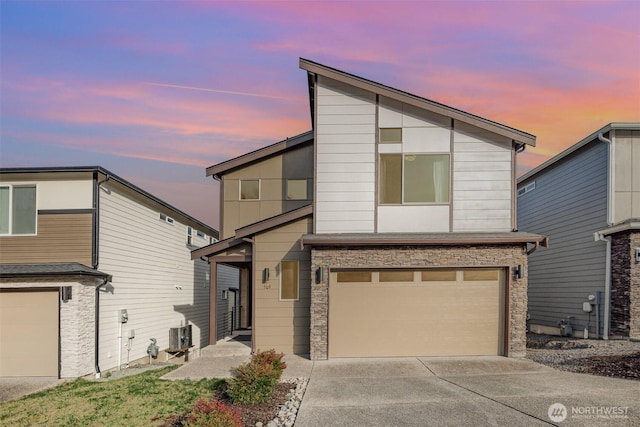 contemporary home featuring cooling unit, an attached garage, and concrete driveway