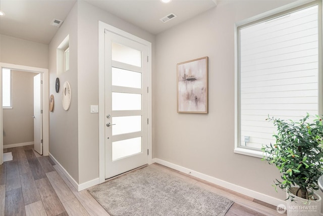 foyer featuring baseboards, visible vents, and light wood finished floors