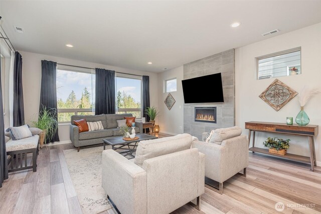 living area featuring recessed lighting, light wood-style flooring, and a fireplace