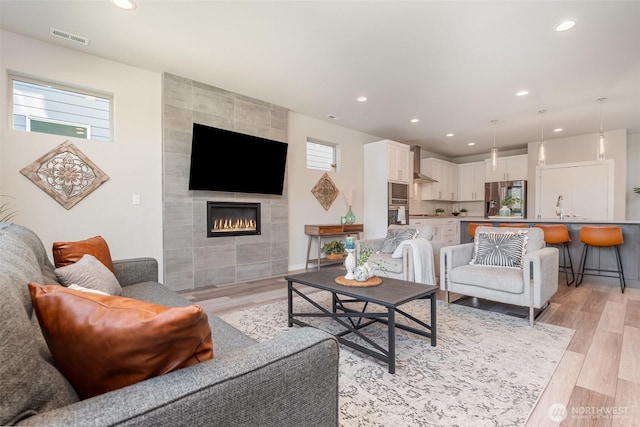 living area featuring recessed lighting, visible vents, light wood-style flooring, and a fireplace