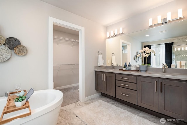 full bathroom featuring a freestanding bath, double vanity, marble finish floor, and a sink