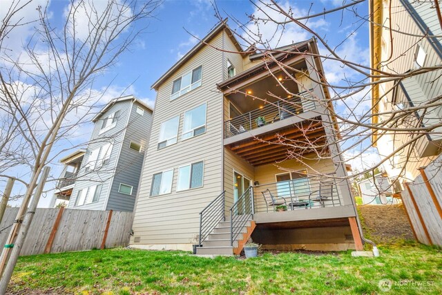 back of property featuring a yard, a balcony, and fence