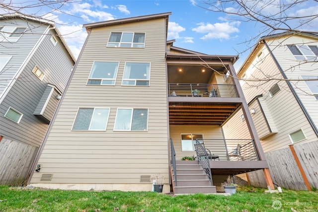 rear view of house featuring a balcony, stairway, fence, and crawl space