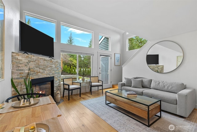 living room featuring a towering ceiling, wood finished floors, and a fireplace