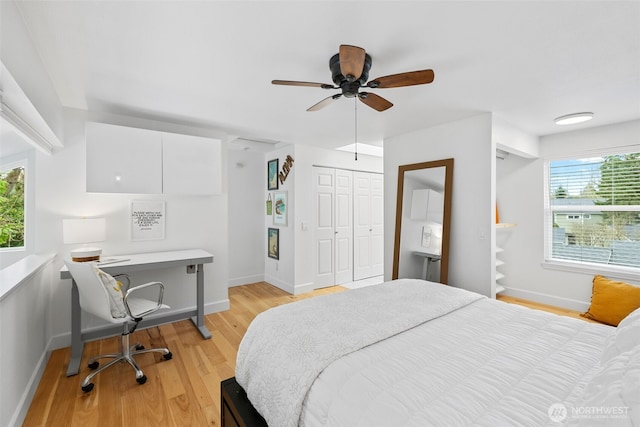 bedroom with light wood finished floors, ceiling fan, a closet, and baseboards