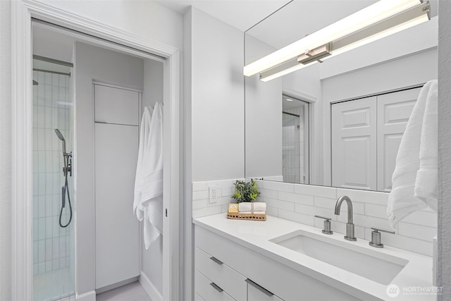 bathroom featuring backsplash, tiled shower, and vanity