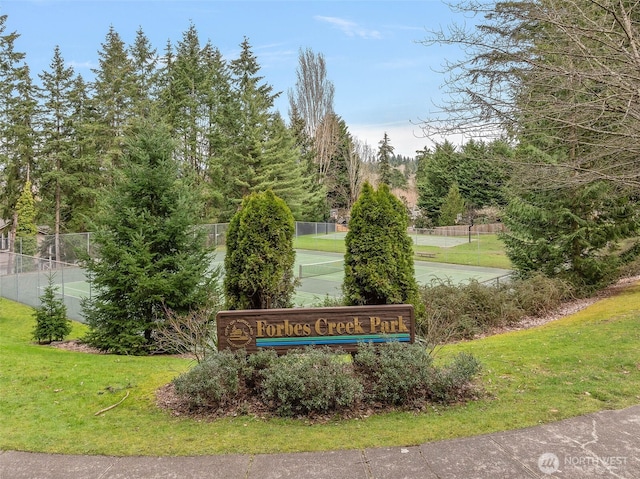 community / neighborhood sign with a yard and fence