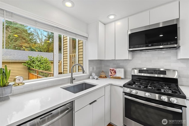 kitchen featuring a sink, stainless steel appliances, white cabinets, light countertops, and decorative backsplash