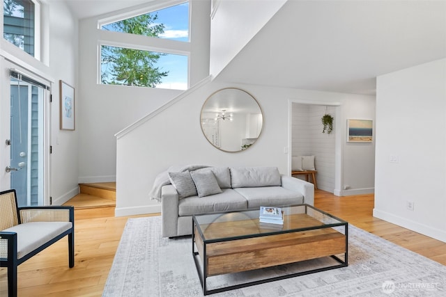 living room featuring a towering ceiling, baseboards, and wood-type flooring