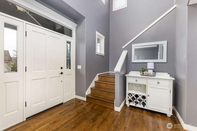 entrance foyer featuring stairs, dark wood-type flooring, and baseboards