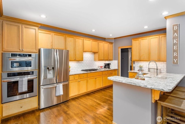 kitchen featuring light stone counters, a peninsula, dark wood-style flooring, stainless steel appliances, and a kitchen bar