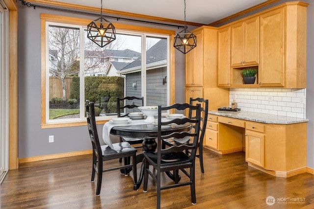 dining space with dark wood finished floors, crown molding, baseboards, and built in desk