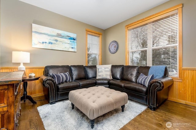 living area featuring wood finished floors, a healthy amount of sunlight, a wainscoted wall, and wood walls