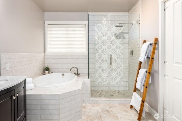 bathroom with a garden tub, a stall shower, and vanity