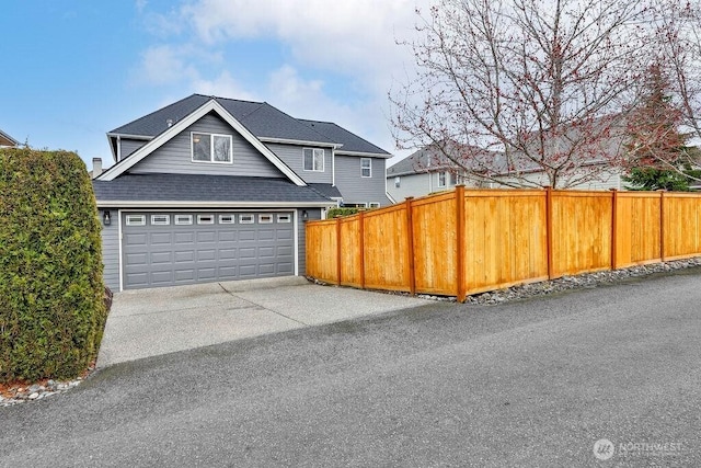 view of front of home with fence, a garage, and a shingled roof