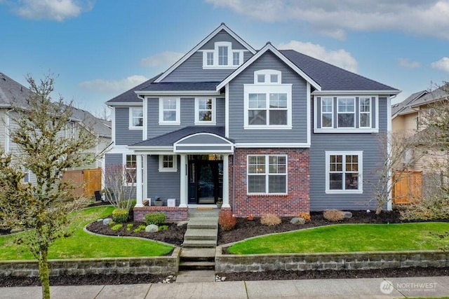 view of front of home featuring brick siding, a front lawn, and fence