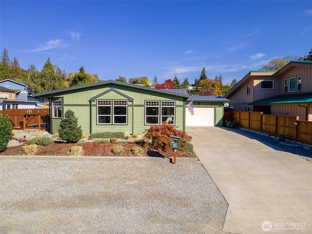 view of front of property with metal roof, concrete driveway, a standing seam roof, and fence