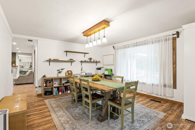 dining space with visible vents, crown molding, baseboards, and wood finished floors