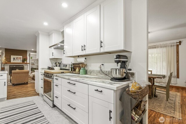 kitchen featuring light wood finished floors, under cabinet range hood, light countertops, electric range, and white cabinets