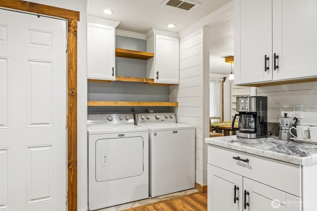 laundry room with visible vents, washing machine and dryer, ornamental molding, laundry area, and light wood-style flooring