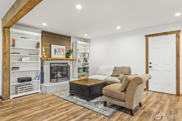 living room with a fireplace, crown molding, recessed lighting, and wood finished floors