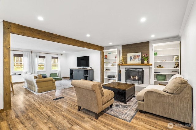 living area with beamed ceiling, recessed lighting, a fireplace, and wood finished floors