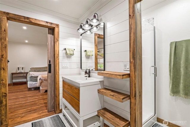 ensuite bathroom featuring ornamental molding, wood finished floors, connected bathroom, a shower stall, and vanity