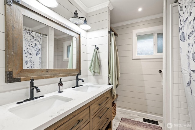 full bath featuring wood walls, crown molding, and a sink