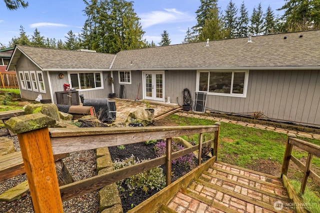 rear view of property featuring french doors, fence, and a shingled roof